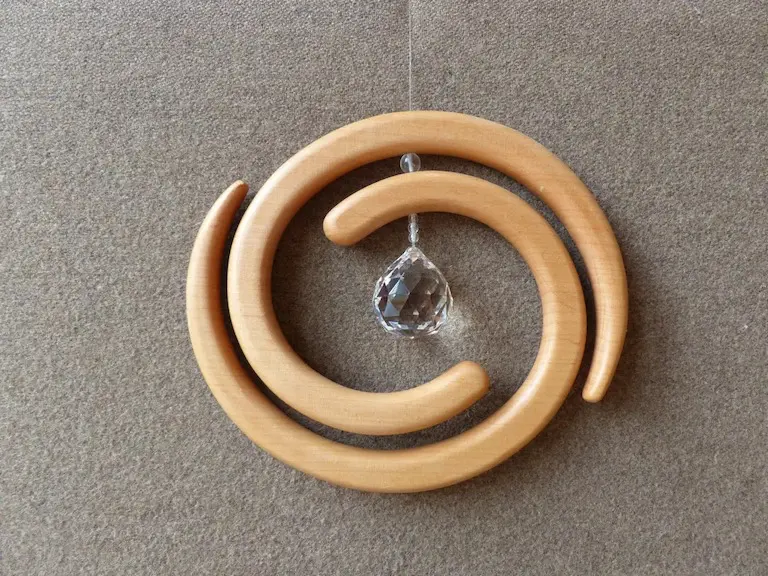 Holzmobile in Spiralenform durch zwei ineinander gedrehte Holzteile mit Schmuckstein