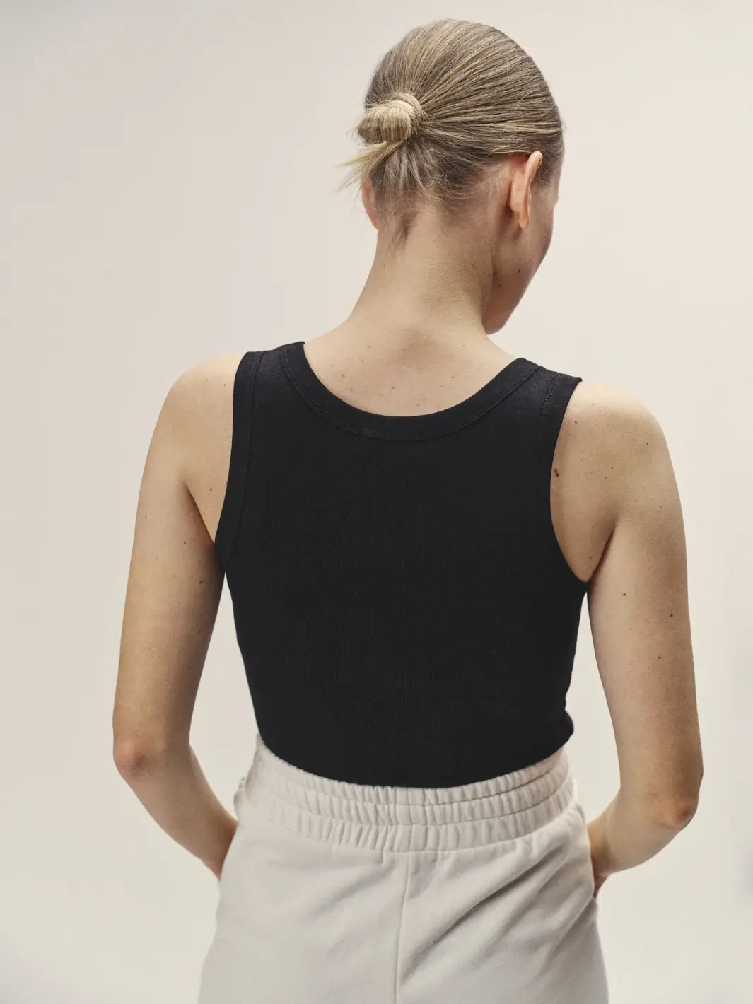 Weibliches Model mit dem Rücken zugewandt, Fokus auf dem schwarzen Top