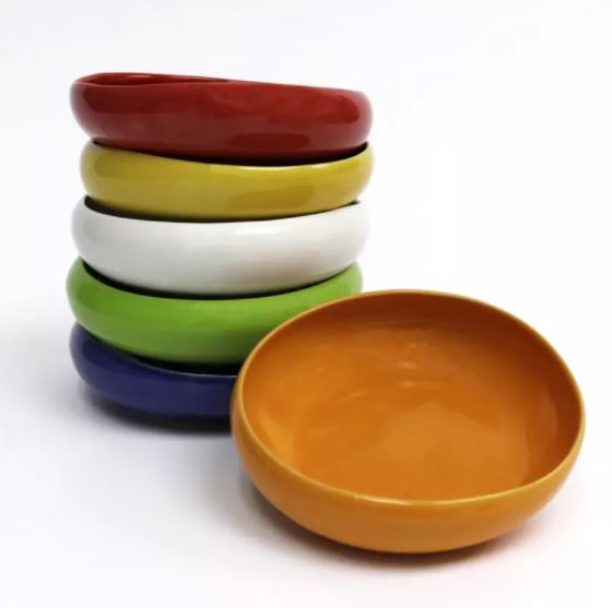 Gestapelte mittelgroße Esshilfe Teller in den Farben orangen, dunkelblau, hellgrün, weiß, gelb und rot