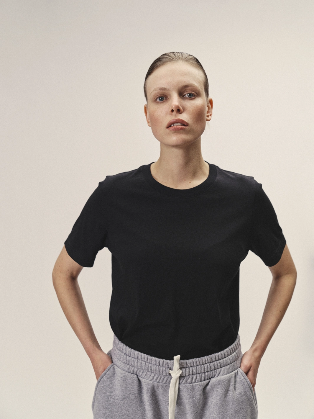 Weibliches Model mit Blick in die Kamera, Fokus auf das schwarze Rundhals-T-Shirt