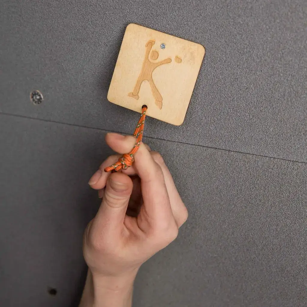 Hand greift Anhängerschnur am quadratisches Holzplättchen mit Personen-Icon