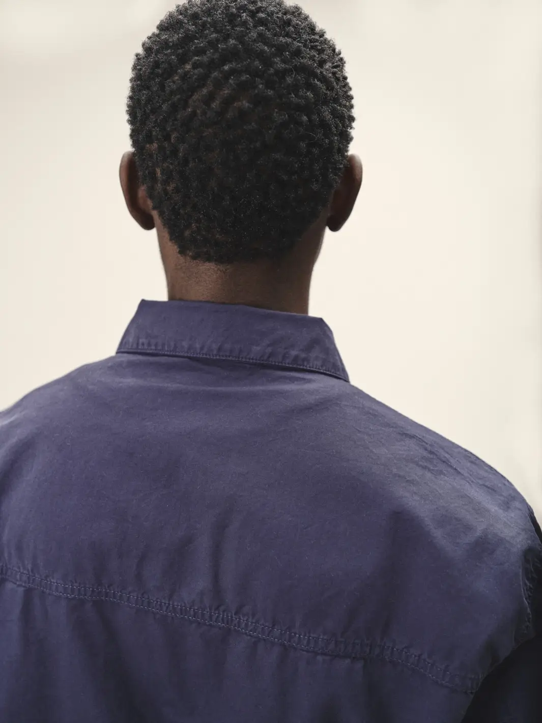 Männliches Model mit dem Rücken zur Kamera, Fokus auf dunkelblauer Jacke