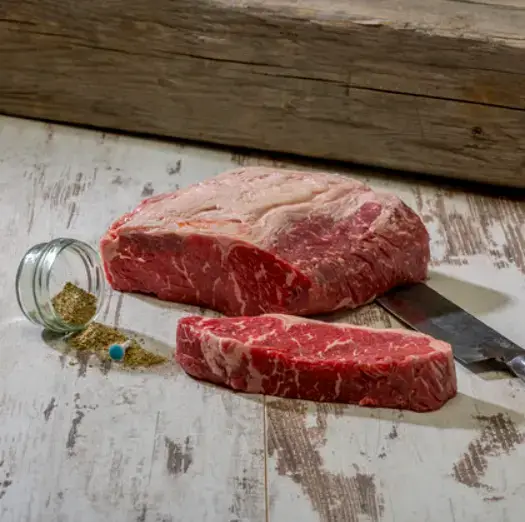 Rohes Steak mit abgeschnittenen Stück und einem Messer daneben