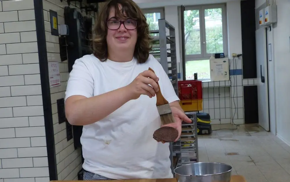 Eine Bewohnerin der Dorfgemeinschaft Hohenroth beim Glasieren der Bio-Lebkuchen in der Bäckerei
