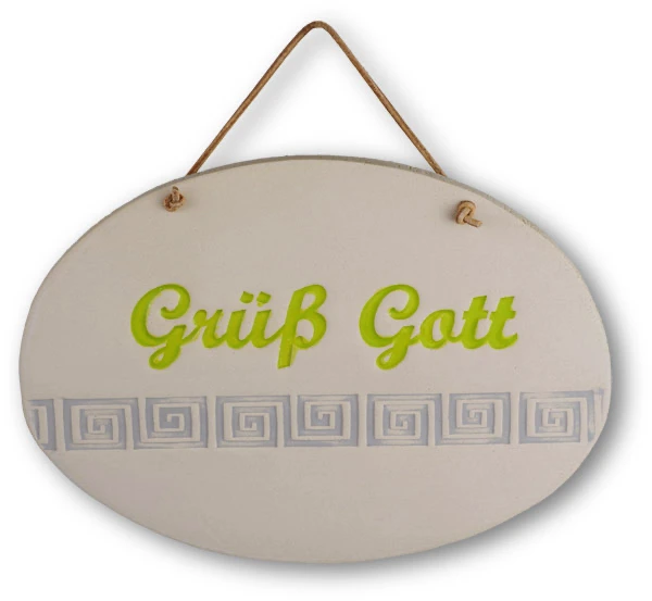 Weißes ovales Tonschild mit grüner Aufschrift "Grüß Gott" mit Ornamenten