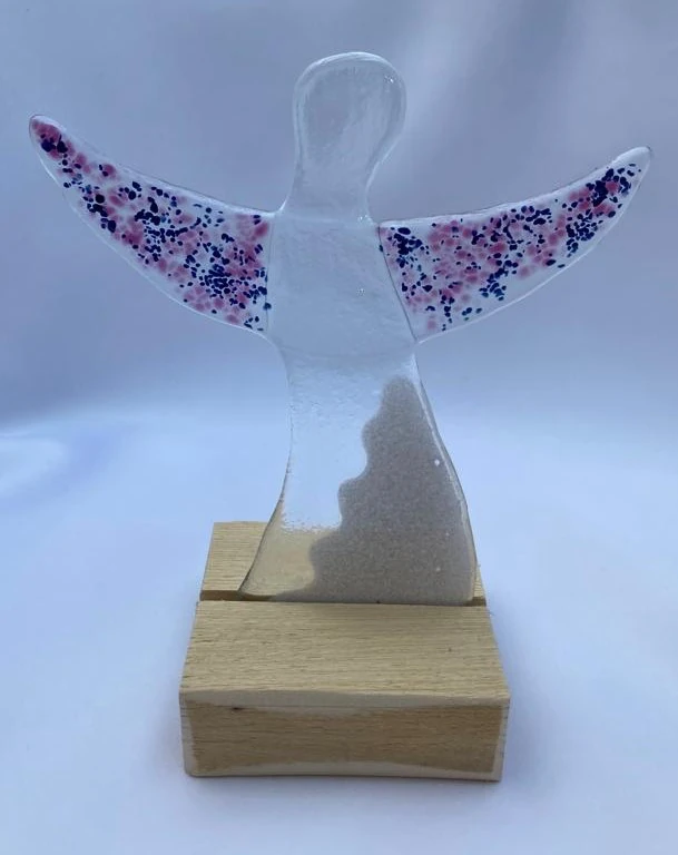 Glasengel mit rosa und dunkelblauen gepunkteten Flügeln und durchsichtigen Körper auf Holzsockel 