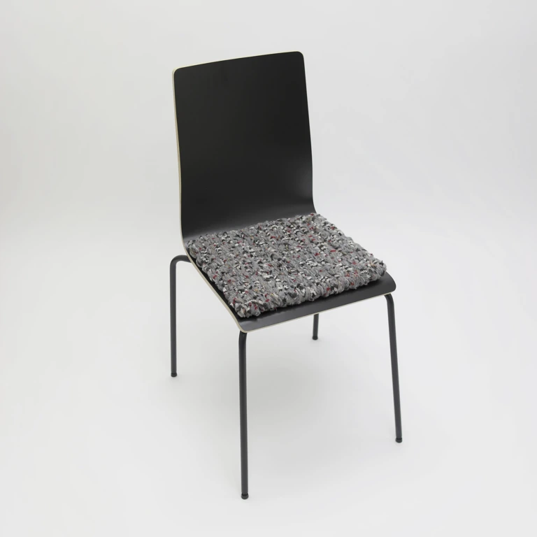 Schwarzer Stuhl mit grauen Stuhlkissen mit weißen, schwarzen und roten Akzenten