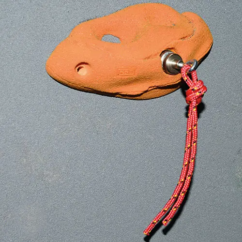Ein Magnet mit roter Schnur an Griffschraube der Kletterwand