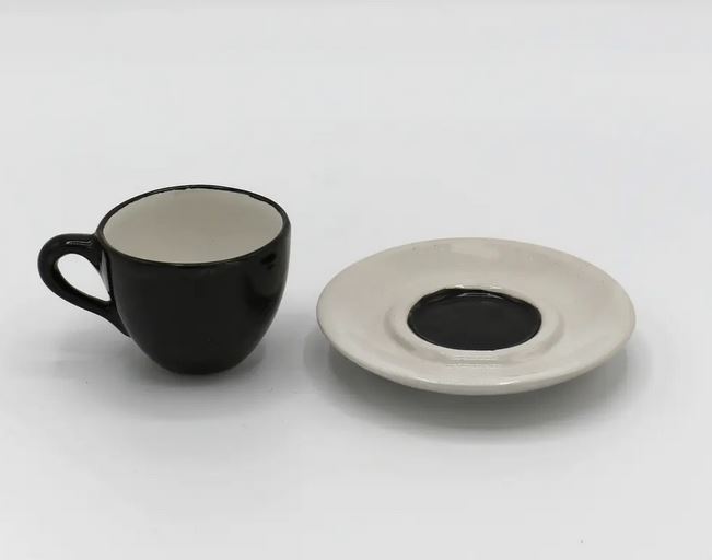 Schwarze Espresso Tasse neben weißem Teller mit schwarzer Mitte für die Tasse