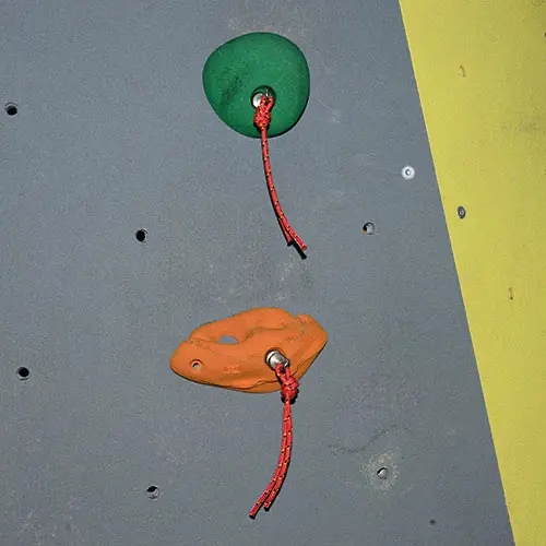Magneten mit roter Schnur an Griffschrauben der Kletterwand