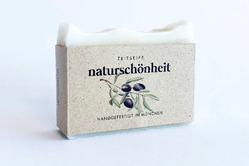 Ein weißer Seifenblock gehüllt in eine Papierverpackung mit floral bedrucktem Etikett