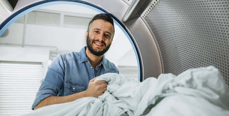 Mann holt Wäsche aus einer Waschmaschine